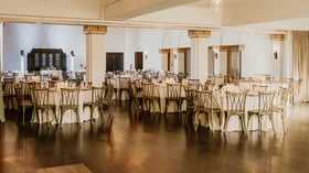 Indoor banquet with ivory linens, crossback chairs, and hardwood flooring at Fillmore Chapel by Wedgewood Events