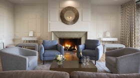 Luxurious pre-function lounge featuring roaring stone fireplace, designer furnishings in soothing gray tones, and contemporary accents - ideal for intimate gatherings and wedding party relaxation