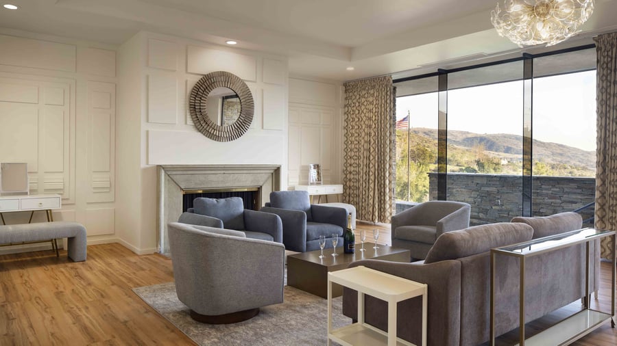 Sophisticated bridal suite featuring elegant vanity with illuminated beauty mirror, fresh floral arrangements, and custom furnishings - creating the perfect space for wedding day preparations and photography