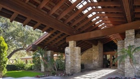 Architectural detail of dramatic exposed beam pavilion entrance with natural stone columns, showcasing the resort's signature blend of rustic elegance and modern sophistication