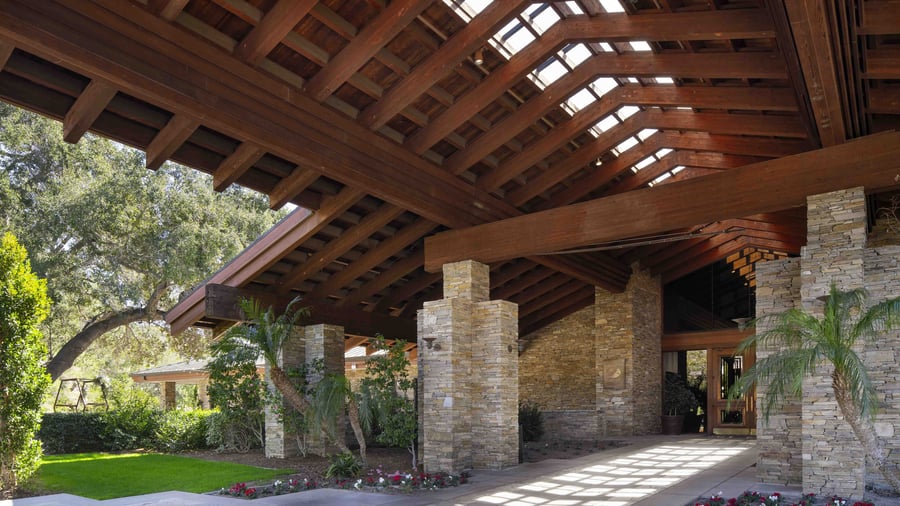 Architectural detail of dramatic exposed beam pavilion entrance with natural stone columns, showcasing the resort's signature blend of rustic elegance and modern sophistication