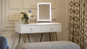 Elegant illuminated vanity station in luxury bridal suite with custom millwork, designer lighting, and fresh floral accents - creating the ideal preparation space for brides and wedding parties