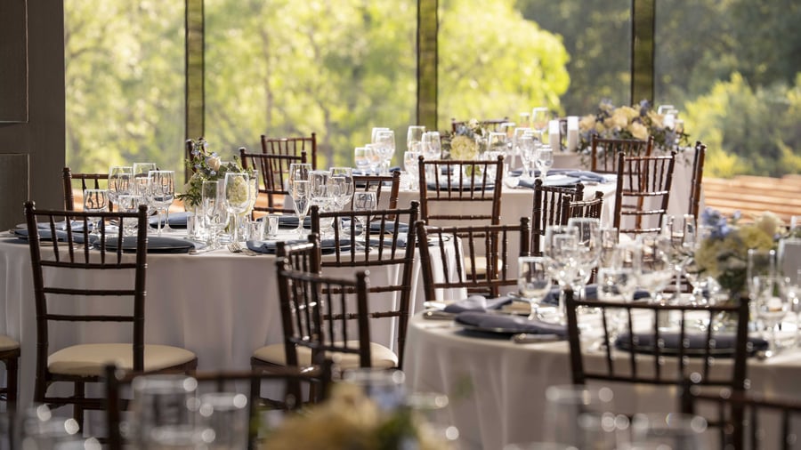 Expansive ballroom with warm wood architectural details, natural light flooding through floor-to-ceiling windows, and versatile open floor plan perfect for grand receptions of up to 200 guests with dedicated dance floor area