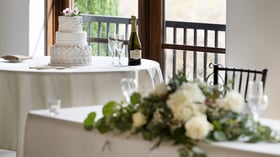 Elegant three-tier celebration cake with white roses and champagne toast setup at Fallbrook Estate by Wedgewood Events featuring tiered cake design and crystal flutes for corporate celebrations and private events