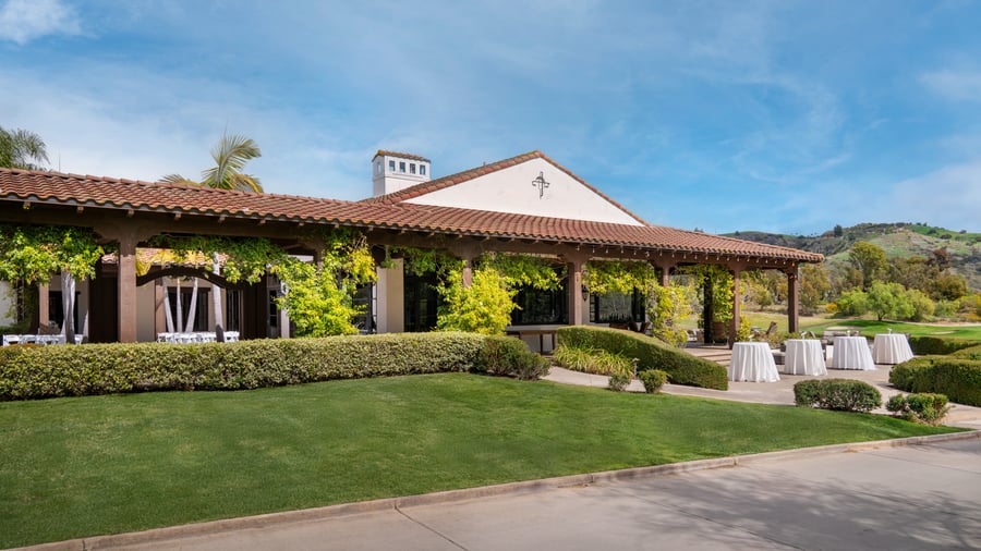 Outdoor event cocktail hour setup at Fallbrook Estate featuring Spanish colonial architecture, covered terrace, cocktail tables and manicured gardens for corporate networking and celebrations