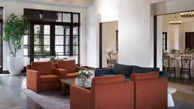 Comfortable event reception lounge at Fallbrook Estate featuring modern furniture, floor-to-ceiling windows, open layout connecting to dining area for corporate networking and private celebrations