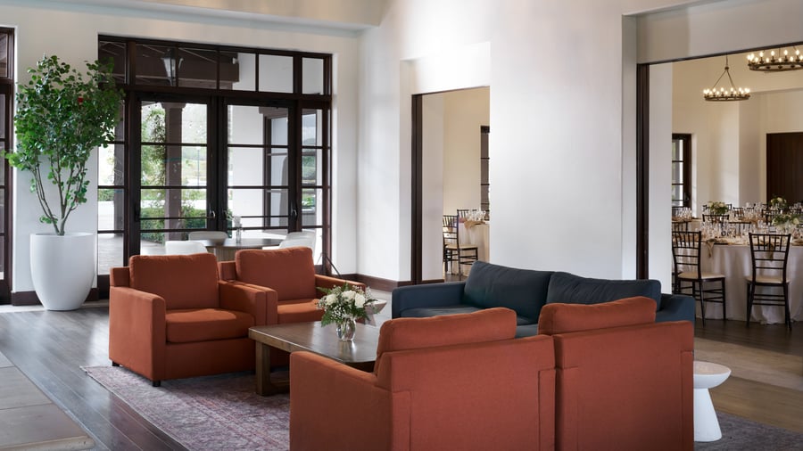 Comfortable event reception lounge at Fallbrook Estate featuring modern furniture, floor-to-ceiling windows, open layout connecting to dining area for corporate networking and private celebrations