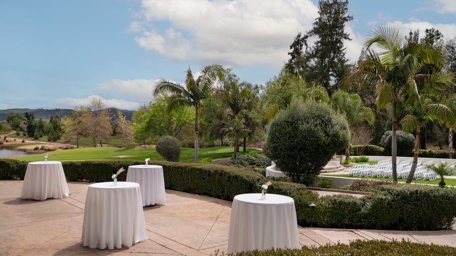 Elegant outdoor event reception patio at Fallbrook Estate Wedgewood Events with cocktail tables, hedge landscaping and scenic golf course views in Fallbrook California for corporate gatherings