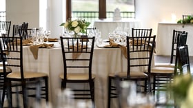 Sophisticated event reception table setting at Fallbrook Estate Wedgewood Events with white roses centerpiece, gold napkins, crystal stemware and elegant chairs for corporate dinners and celebrations