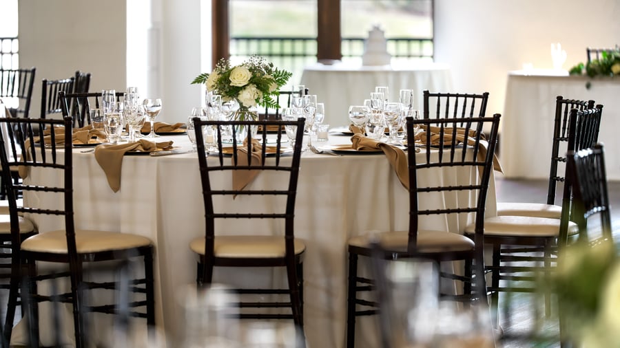 Sophisticated event reception table setting at Fallbrook Estate Wedgewood Events with white roses centerpiece, gold napkins, crystal stemware and elegant chairs for corporate dinners and celebrations