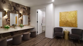 Sophisticated event preparation room at Fallbrook Estate by Wedgewood Events featuring modern vanity area, gold accent wall, comfortable seating and premium amenities for corporate events and celebrations