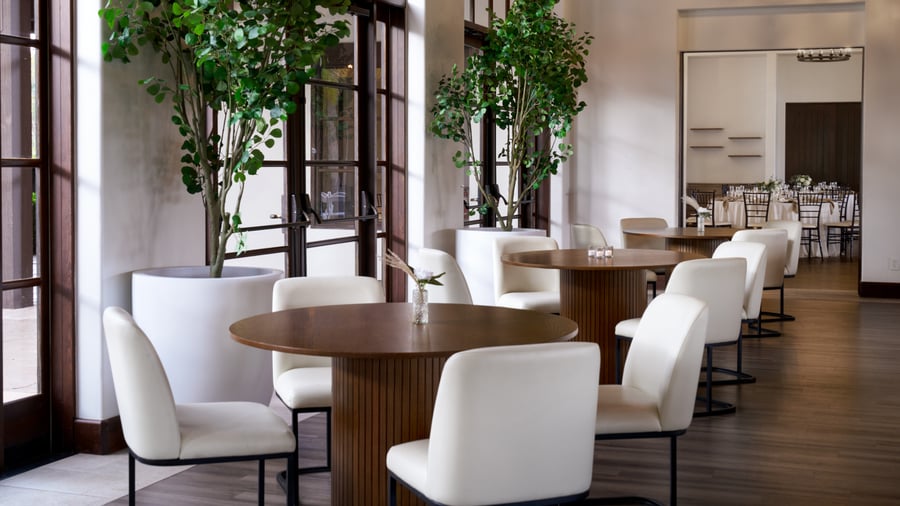 Contemporary event cocktail lounge at Fallbrook Estate featuring round high-top tables, cream upholstered chairs, floor-to-ceiling windows for corporate networking events and private celebrations