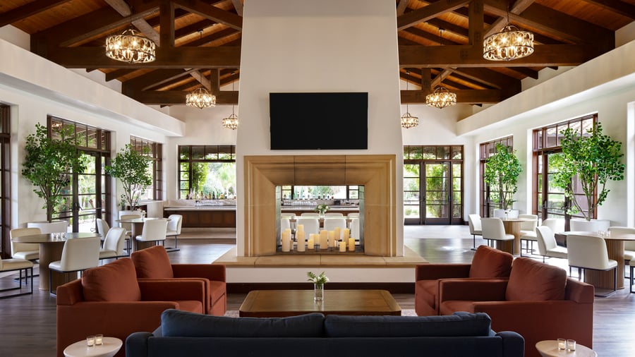 Contemporary event reception lounge at Fallbrook Estate featuring exposed wood beams, geometric chandeliers, modern furniture, two-way fireplace and floor-to-ceiling windows for corporate events and private parties
