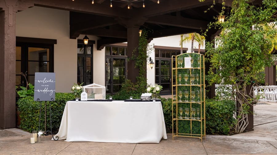 Beautiful outdoor event welcome station at Fallbrook Estate featuring welcome signage, gold geometric display, covered patio with string lights for corporate events and private celebrations