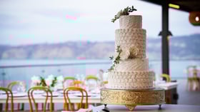  Four-tier white wedding cake with floral decorations and ocean backdrop
