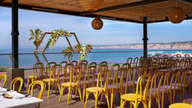Ceremony space with floral arch and guest seating facing Pacific Ocean