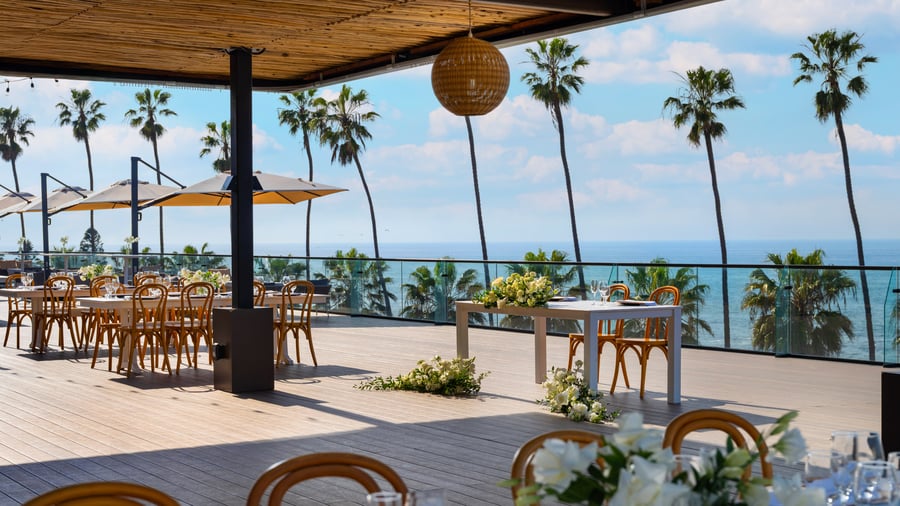 Covered dining area with pendant lights and sweeping coastal views