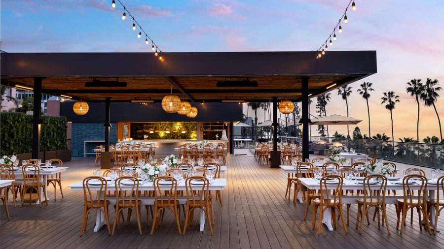 Evening rooftop dining setup with string lights and palm tree silhouettes