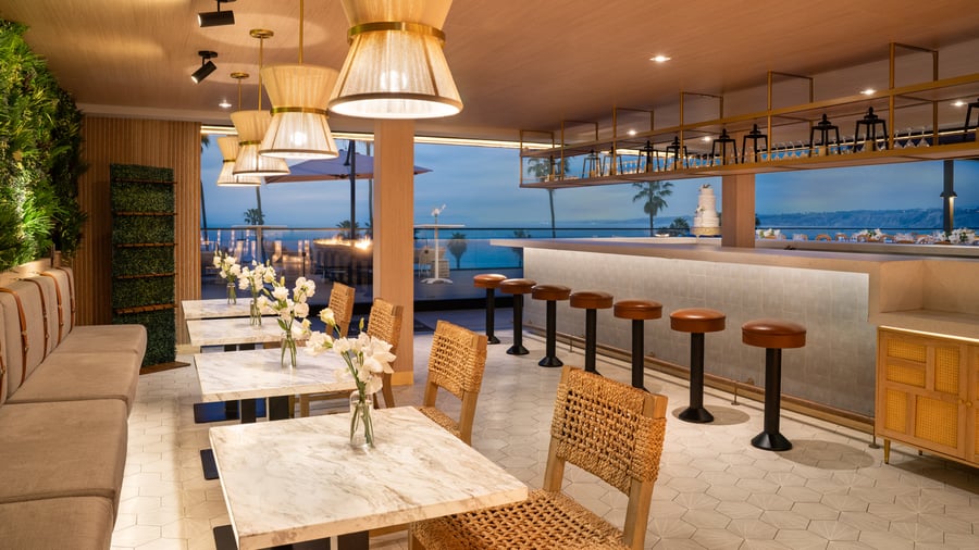 Indoor bar area with pendant lighting and coastal view through large windows