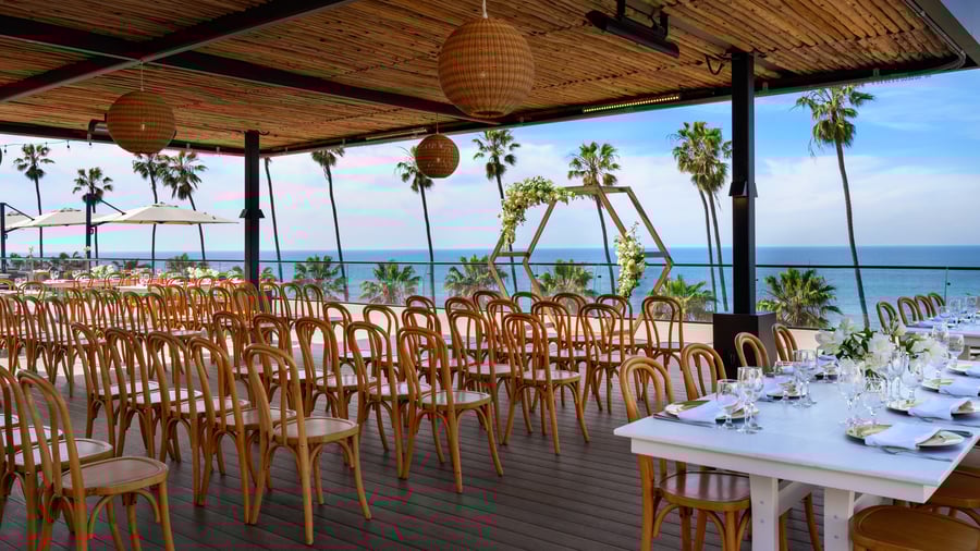 Daytime ceremony setup with hexagonal arch and rows of wooden chairs