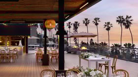 Sunset reception with dining tables and lounge areas on oceanfront deck