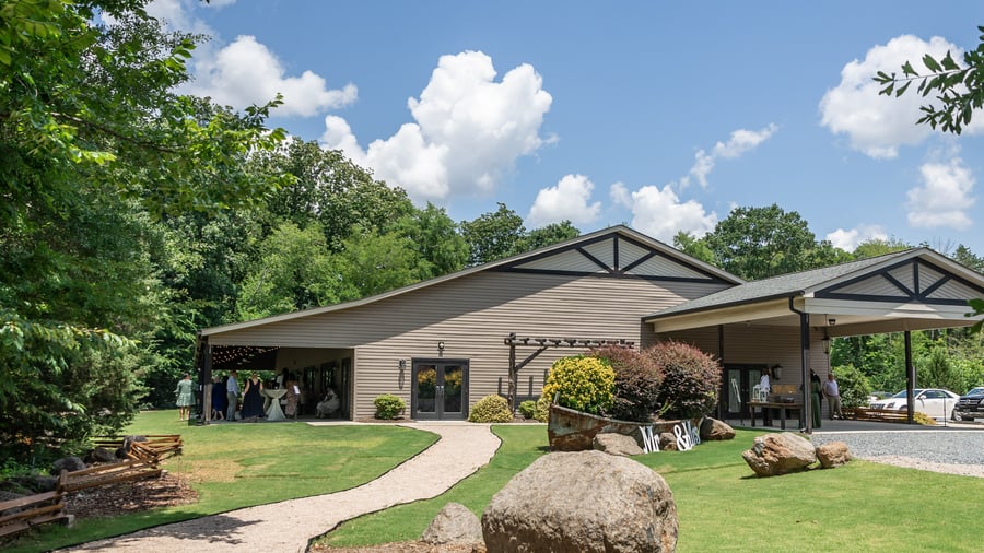 Exterior of Riverwood Manor's main building surrounded by manicured lawns, landscaped grounds, and natural stone elements, providing a welcoming entrance for event guests in Harrisburg, North Carolina - Ken Thomas Photography
