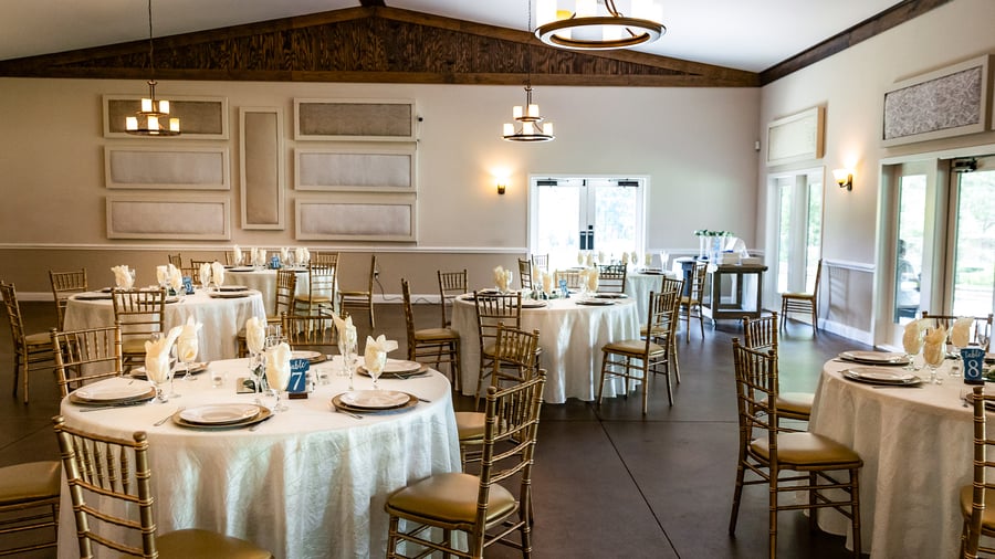 Event space at Riverwood Manor showcasing round tables with white linens, gold chairs, and formal place settings for corporate functions, galas, and special celebrations - Ken Thomas Photography