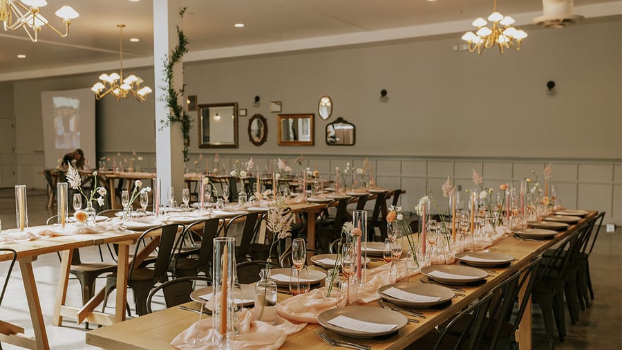 Intimate reception room with vintage-inspired decor, featuring wooden tables, metal chairs, and an eclectic gallery wall of mirrors
